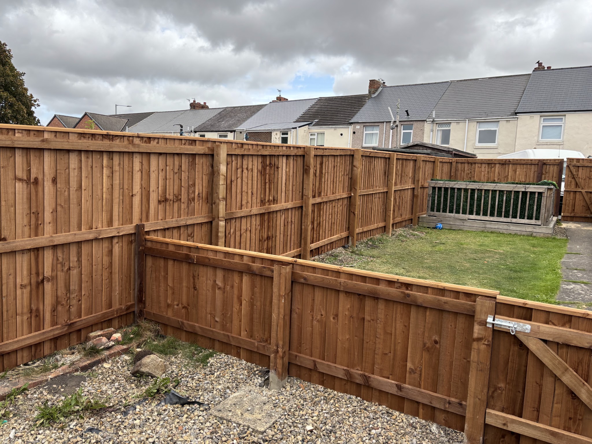 A long run of new close-boarded fencing with a matching gate, enclosing a back garden in a row of terraced houses