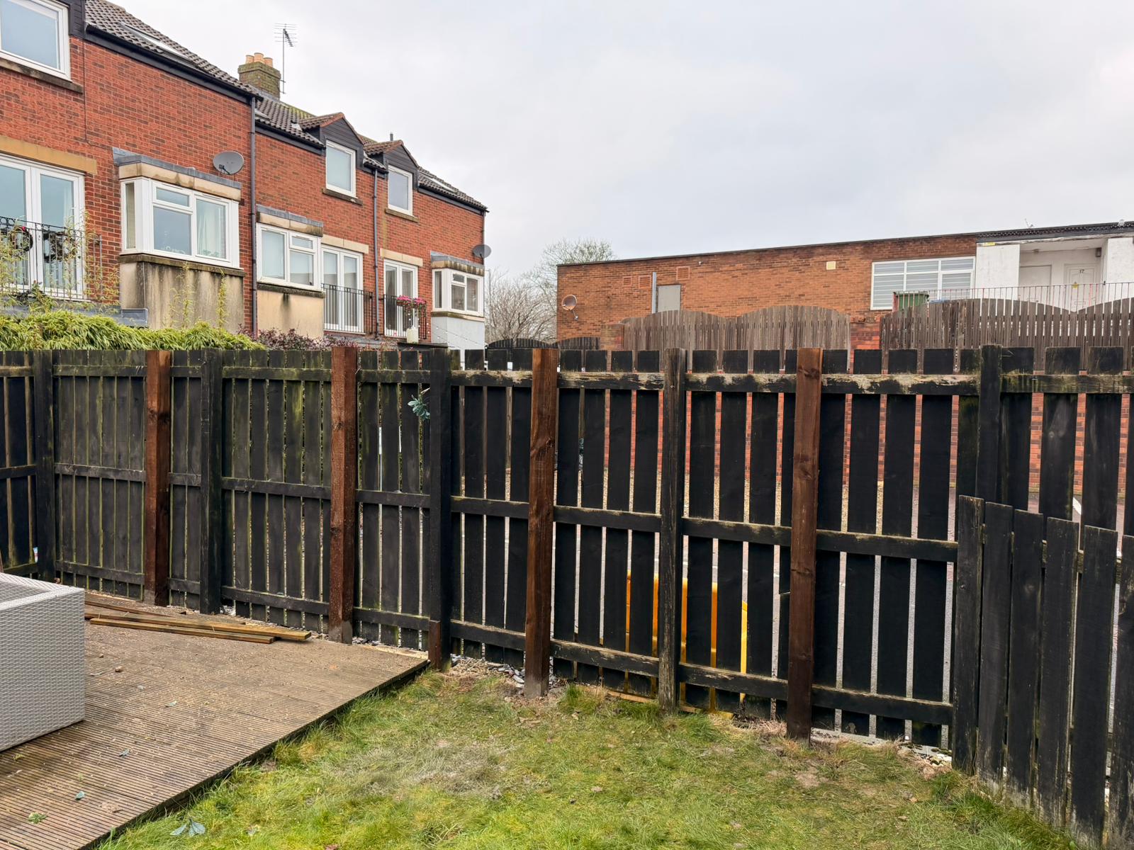 Dark-stained paled fence and gate along the back of a patio garden