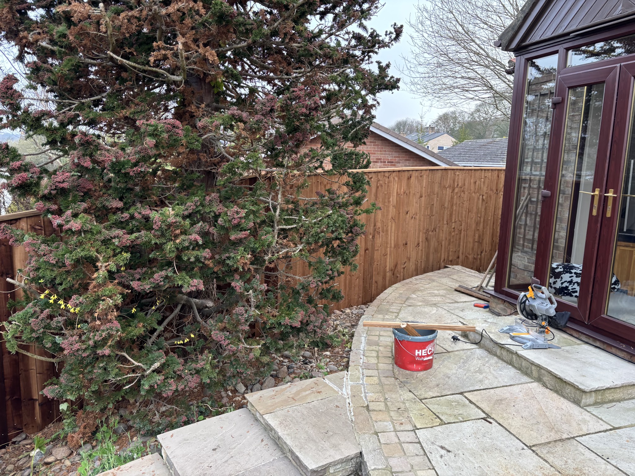New fencing around a paved patio next to a conservatory